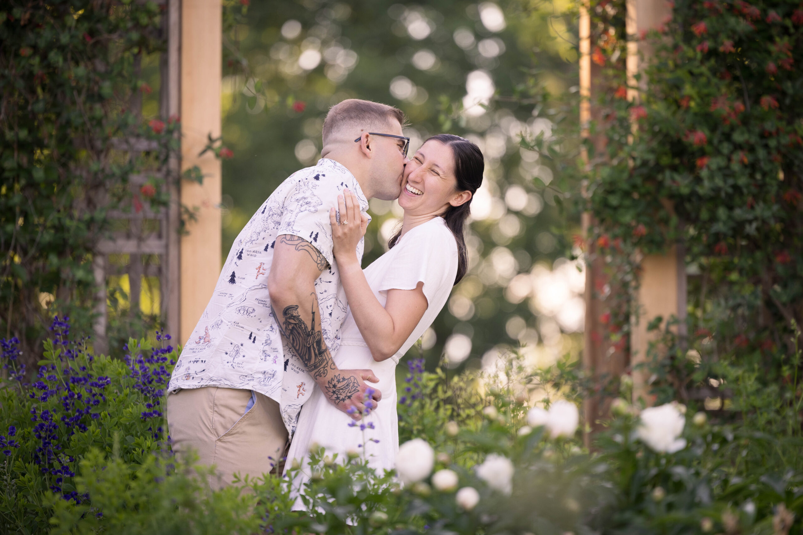 Joyful couple posing during golden hour engagement shoot with colorful flowers in the background